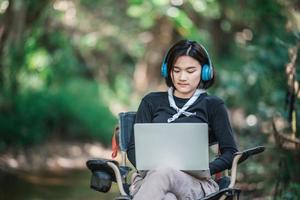 Young woman wearing headphone listening music from laptop photo