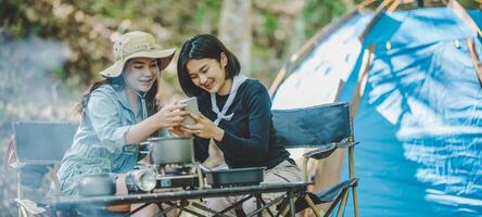 Asian pretty woman and friend use smartphone selfie on camping photo