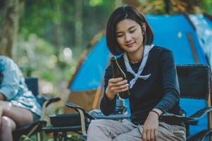 Young women sitting and drink beverage  front of camping tent photo