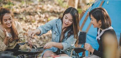 Young women enjoy to cooking meal on camping photo