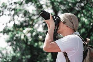 Asian traveler man with backpack taking a photo in the park