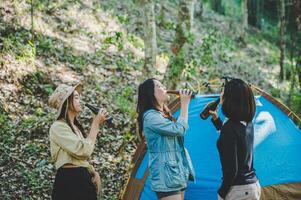 Young woman cheer and drink beverage front of camping tent photo