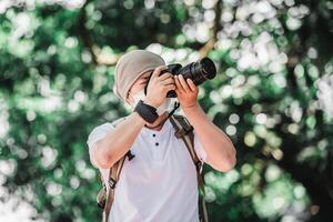 hombre viajero asiático con mochila tomando una foto en el parque