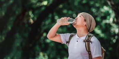 Portrait Asian traveler man with backpack drinking water photo