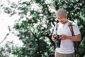 hombre viajero asiático revisando una foto en la cámara en el parque