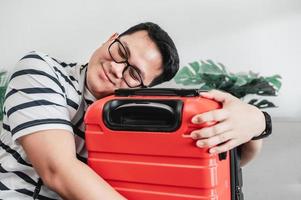 Happy Asian traveler man glasses hugging luggage photo
