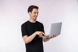Portrait of young handsome smiling man holding laptop in hands, typing and browsing web pages isolated on white background photo