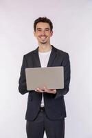 Portrait of young handsome smiling businessman holding laptop in hands, typing and browsing web pages isolated on white background photo