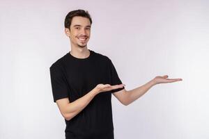 Portrait of happy smiling young man presenting and showing your text or product isolated on white background photo