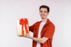 retrato de un joven caucásico feliz que muestra la caja de regalo y mira la cámara aislada sobre el fondo blanco foto