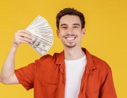 Portrait of a cheerful man holding dollar bills over yellow background photo