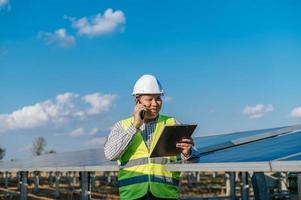 Young engineer talking on smartphone while working at solar farm photo
