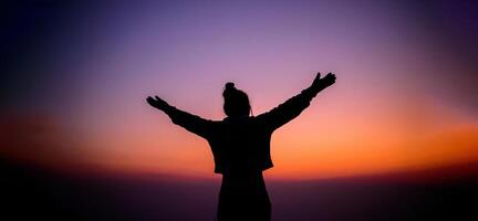 Silhouette of cheering hiking woman open arms to the sunrise stand on mountain photo