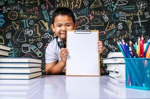 Child sitting and showing clip board in the classroom photo