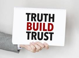 man's hand holding paper sheet with truth build trust words photo