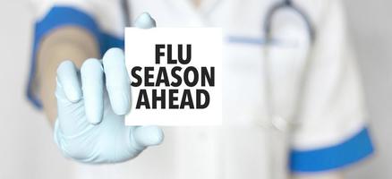 Sign flu season ahead and hand with stethoscope of Medical Doctor photo