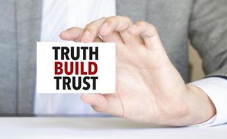 man's hand holding paper sheet with truth build trust words photo