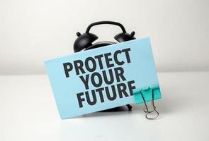 proteger tu futuro es escrito en un azul pegatina cerca un negro alarma reloj foto
