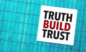 truth build trust word on torn paper with blue wooden background photo