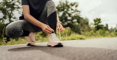 mujer corredor atadura cordones de los zapatos en la carretera foto