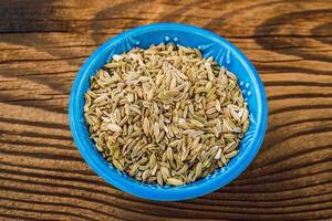 Dried fennel seeds in a bowl on a wooden board photo