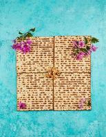 Pesach celebration concept - Jewish holiday Pesach. Four square folded matzahs with flowers. View from above. Flat layout. photo