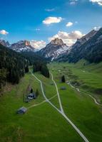 Aerial view of a valley, houses standing on a meadow hiking trails and streams leading towards mountains photo