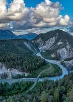 A river that runs in a S curve between the mountains,a railroad bridge crosses the river photo