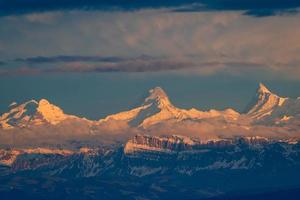 alto macante montañas cubierto con nieve durante un puesta de sol foto