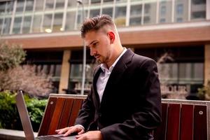 joven empresario en el parque trabajando en el computadora foto