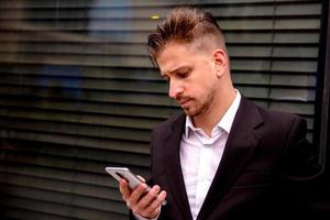 a guy in a suit looks at the phone emotionally photo