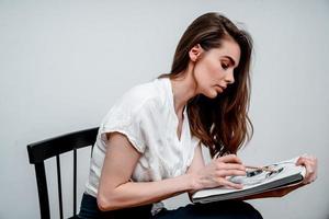 Girl sitting on a chair draws a sketch for a picture photo