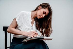 Girl sitting on a chair draws a sketch for a picture photo