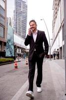 guy in a suit talks on the phone laughs and walks photo