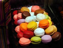 Stack of vibrant Multicolored macaroons, colorful french cookies macarons in dark background displayed in Spanish pastry shop photo