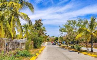 Colorful street with houses palms cars restaurants Puerto Escondido Mexico. photo