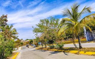 Colorful street with houses palms cars restaurants Puerto Escondido Mexico. photo