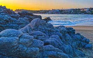 Colorful golden sunset big wave rocks beach Puerto Escondido Mexico. photo