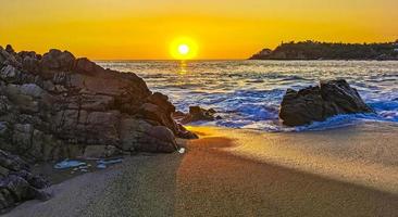 Colorful golden sunset big wave rocks beach Puerto Escondido Mexico. photo