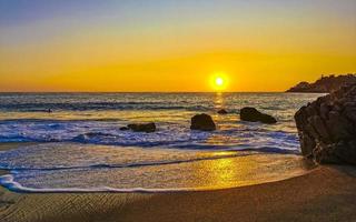 vistoso dorado puesta de sol grande ola rocas playa puerto escondido México. foto