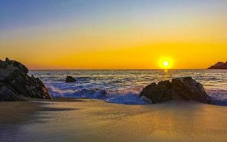 Colorful golden sunset big wave rocks beach Puerto Escondido Mexico. photo