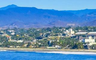 Sun beach cliffs rocks waves palms mountains Puerto Escondido Mexico. photo