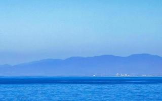 Sun beach cliffs rocks waves palms mountains Puerto Escondido Mexico. photo