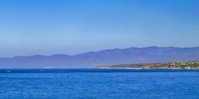 Sun beach cliffs rocks waves palms mountains Puerto Escondido Mexico. photo