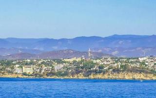 Sun beach cliffs rocks waves palms mountains Puerto Escondido Mexico. photo