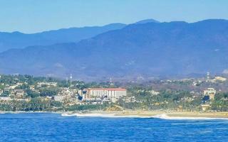 Sun beach cliffs rocks waves palms mountains Puerto Escondido Mexico. photo