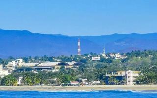 Sun beach cliffs rocks waves palms mountains Puerto Escondido Mexico. photo