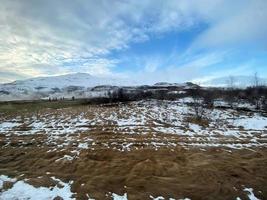 Icelandic winter landscape with snow covered hills and blue cloudy sky photo