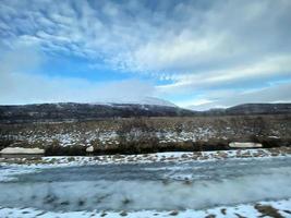 Icelandic winter landscape with snow covered hills and blue cloudy sky photo