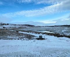 Icelandic winter landscape with snow covered hills and blue cloudy sky photo